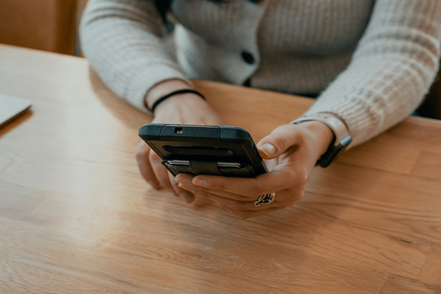 Hands at a table holding a phone.